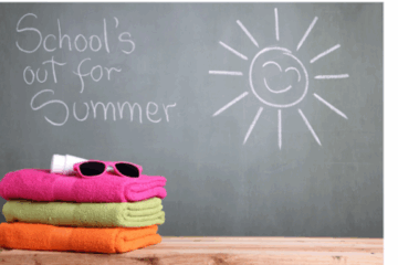 Tableau vert avec “School’s out for summer” et un soleil souriant dessiné à la craie, à côté de serviettes empilées, lunettes roses et crème solaire.